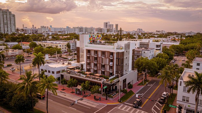 Aerial sunset view of Upsun Hotel showing full building with facade louvers, terrace railings, and rooftop pool deck - Miami Beach FL