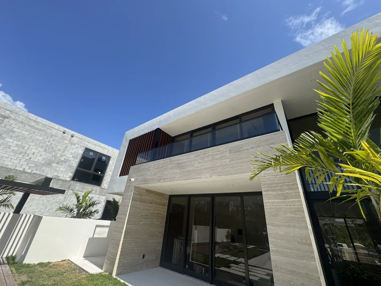 Travertine facade with glass balcony railing and faux-wood louver screen - Atlantic Ave Residence gallery