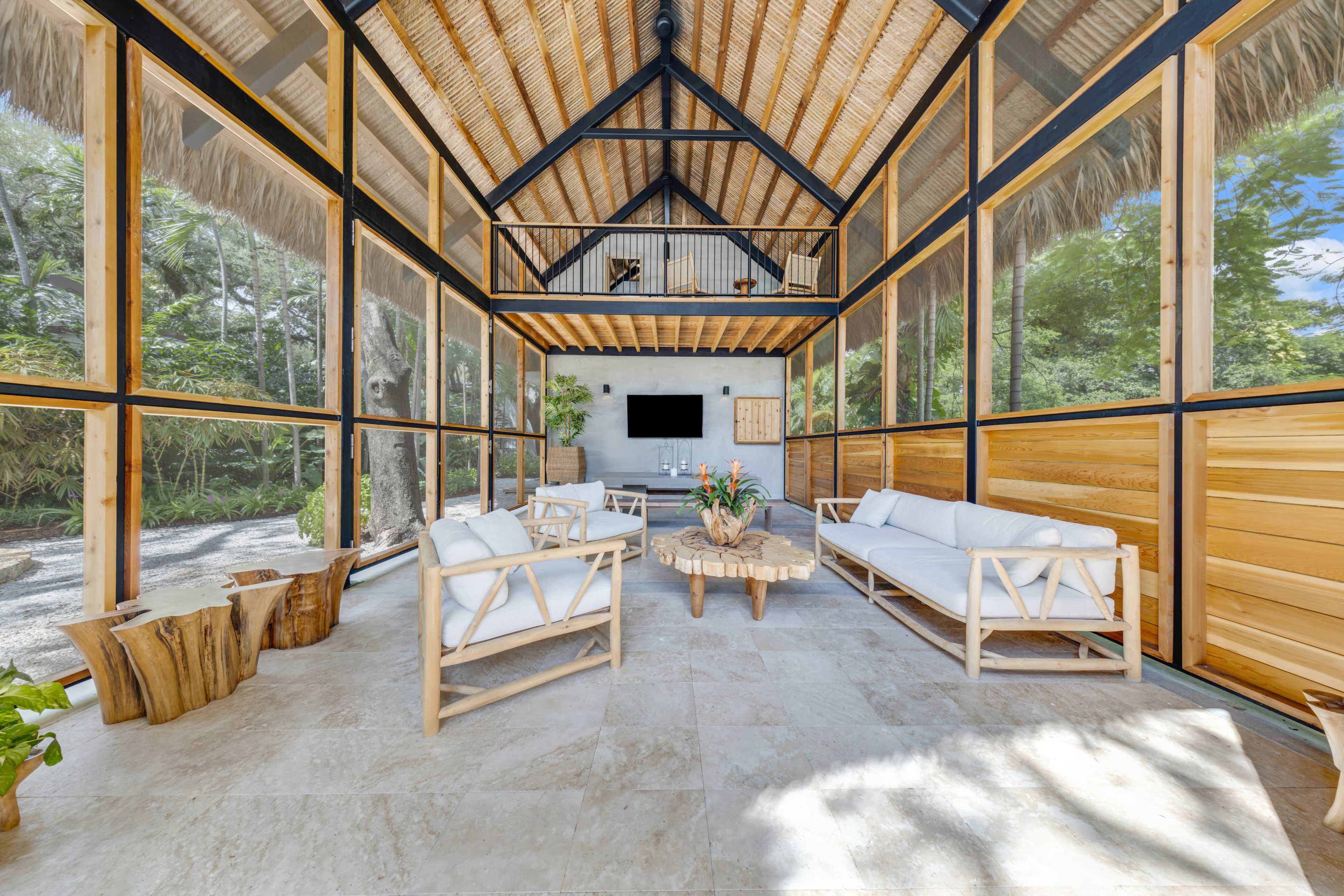 Carport lounge interior with steel frame, thatch roof, and cedar louvers - Jungle Book Residence, Miami FL