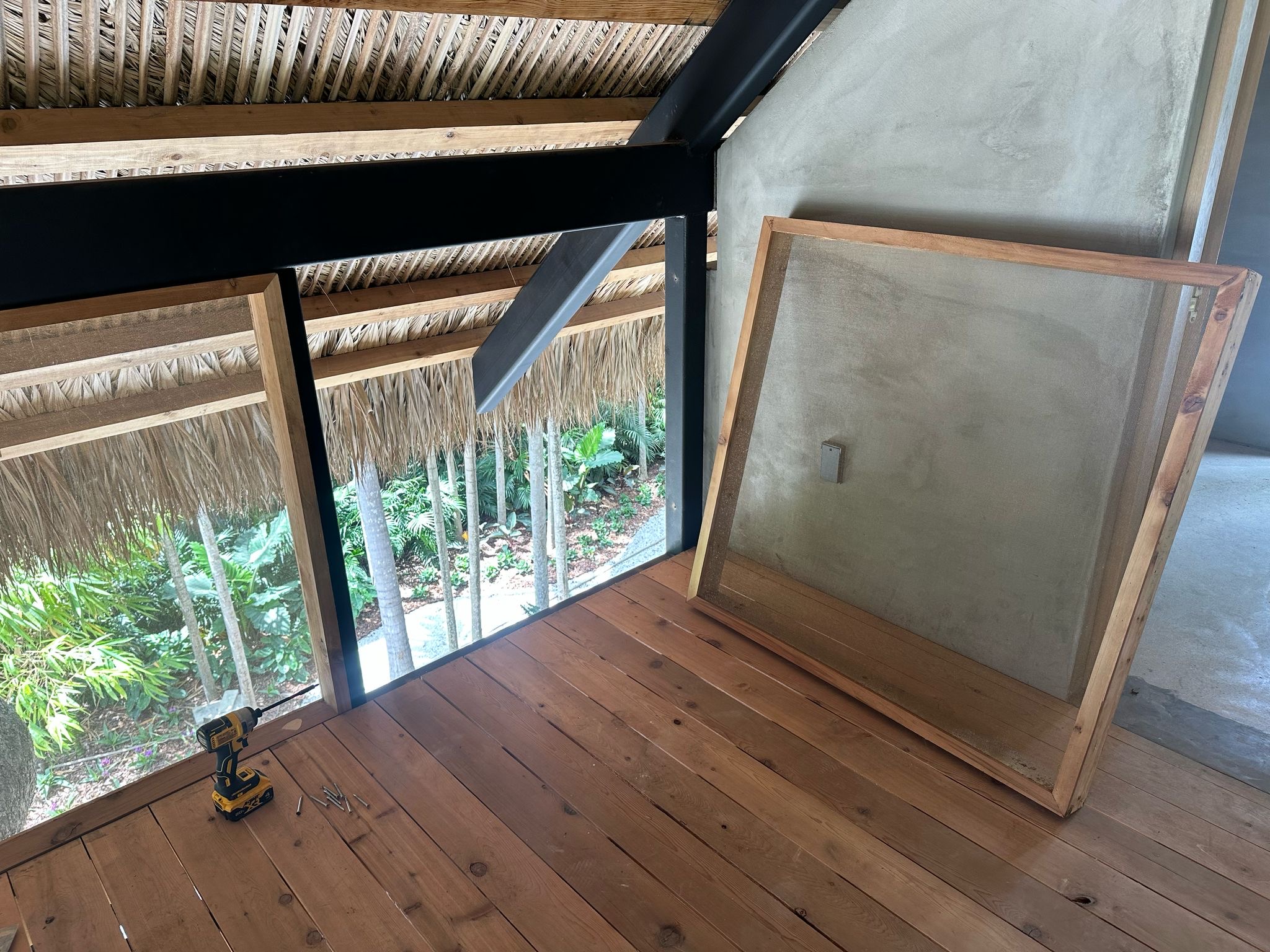 Carport interior with steel frame, wood panels, and thatch roof — Jungle Book Residence, Miami FL