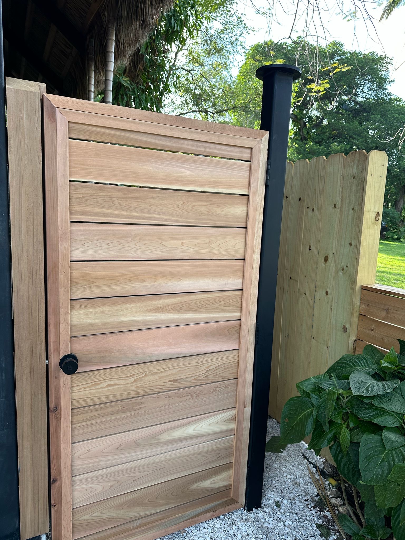 Custom cedar gate with lock hardware and tiki thatch — Jungle Book Residence, Miami FL