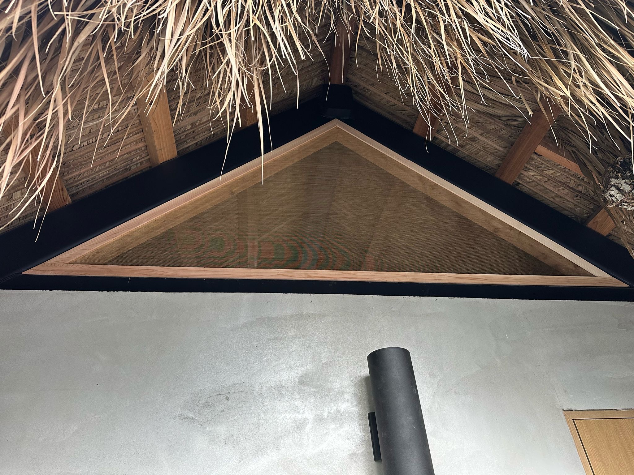 Triangular wood-and-mesh gable panel under thatch canopy — Jungle Book Residence, Miami FL