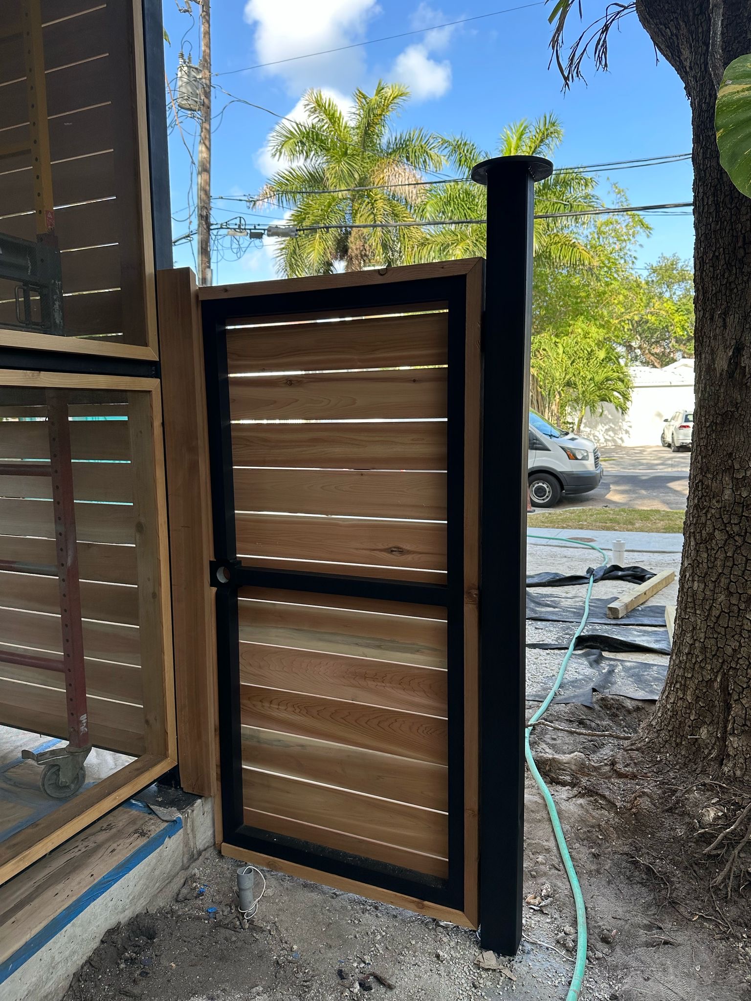 Cedar louver fence gate with black steel frame and post cap — Jungle Book Residence, Miami FL