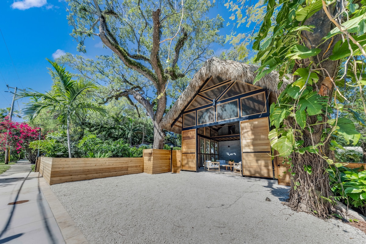 Carport exterior with steel frame, cedar fences, and thatched roof — Jungle Book Residence, Miami FL