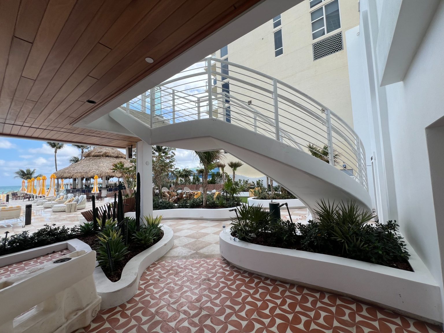 Curved white staircase and poolside lounge at Newport Beachside Resort
