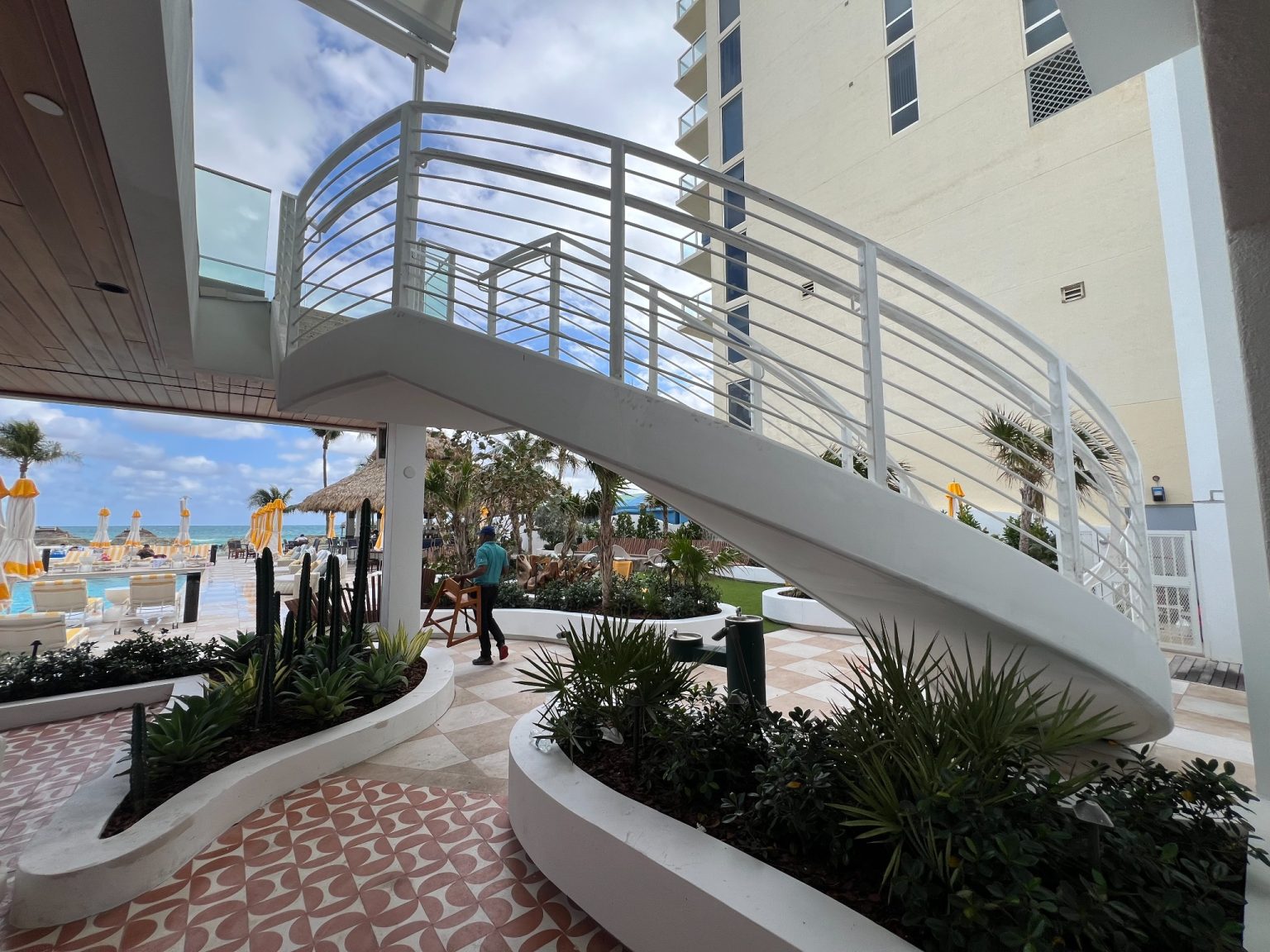 Curved white staircase with beach view and lush landscaping