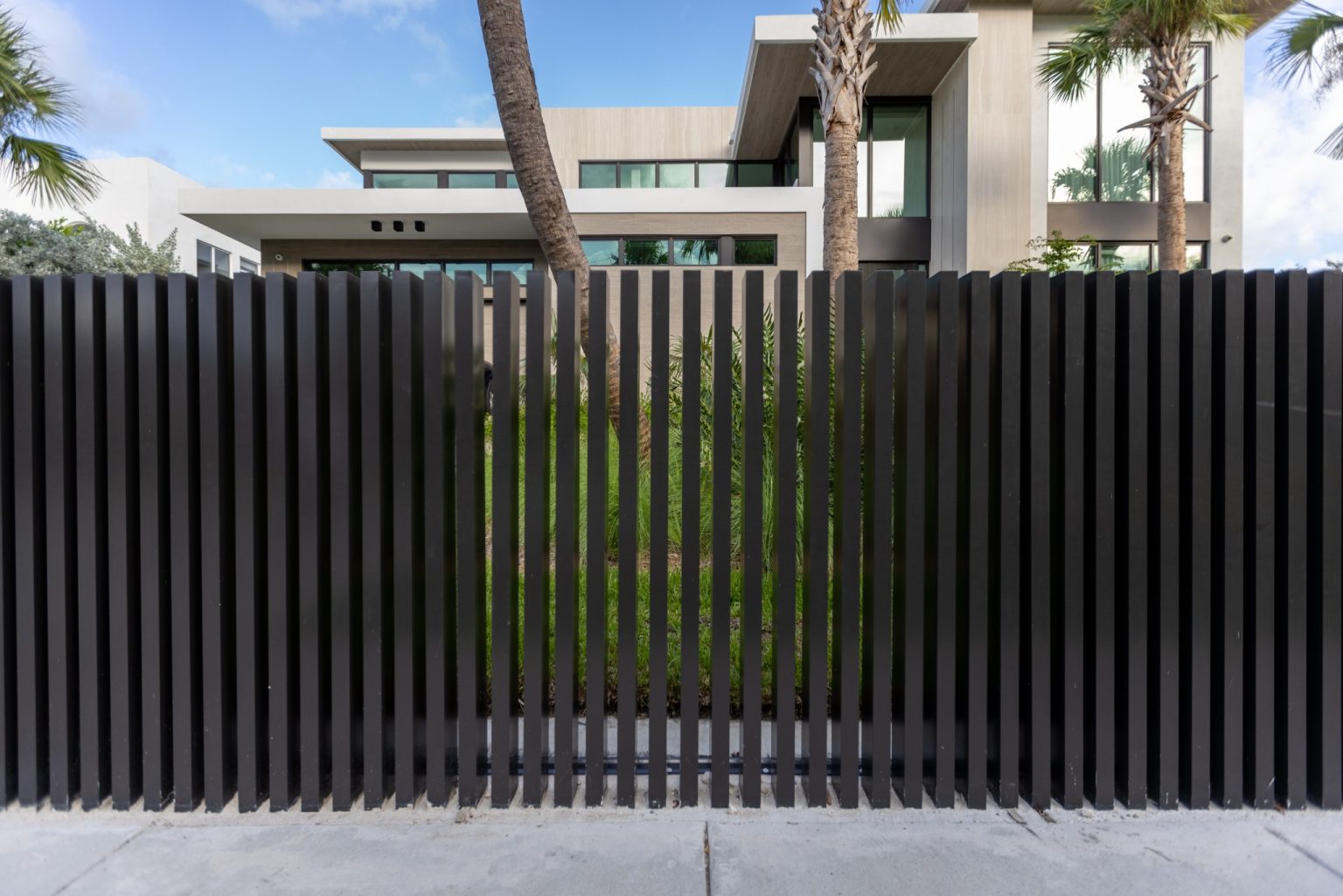 Detailed view of sleek black aluminum slat fence along sidewalk at North Bay Village residence in Miami