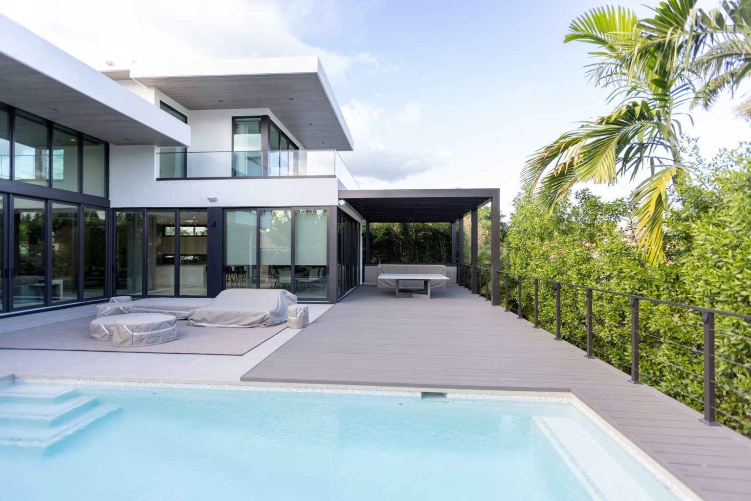 Pool deck with cable railing and pergola at North Bay Village residence in Miami